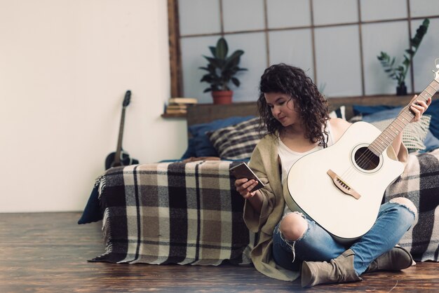 Woman with guitar and mobile phone