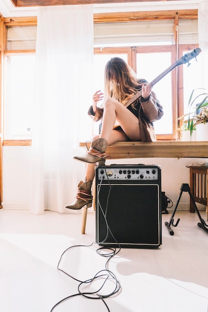 Free photo woman with guitar sitting on table