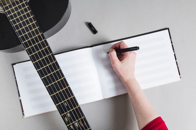 Woman with guitar writing down notes