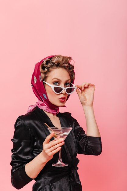 Woman with hair curlers on her head takes off glasses and looks at front