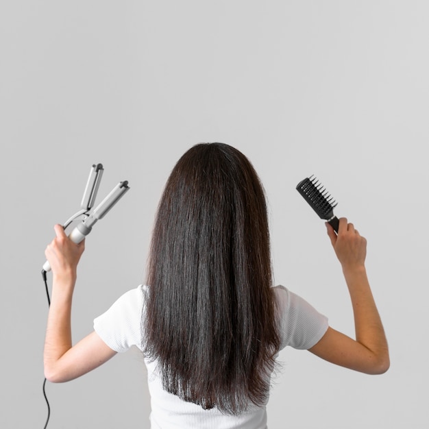 ストレートヘアアイロンを持つ女性