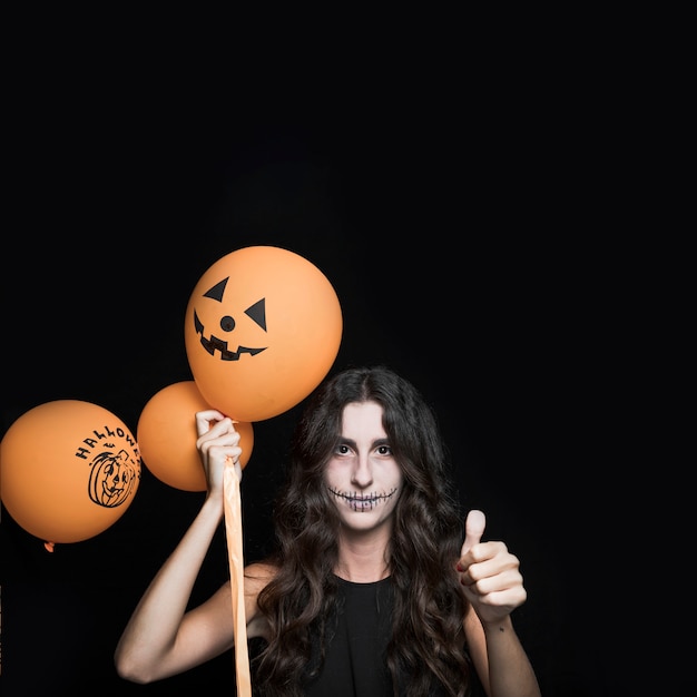 Foto gratuita donna con palloncini di halloween mostrando buon segno