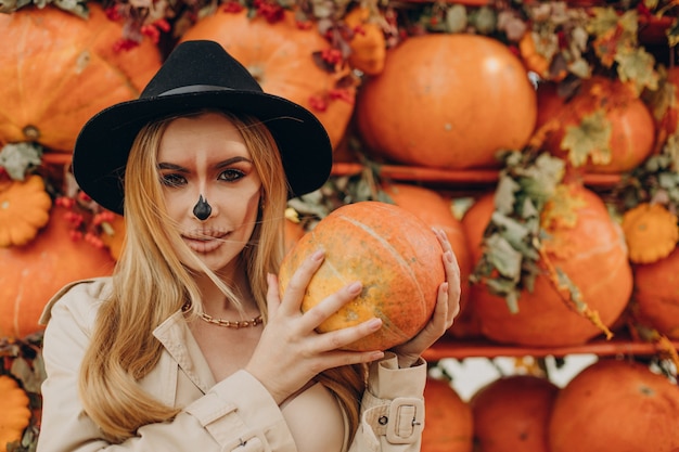 Free photo woman with halloween make up standing by halloween pumpkins