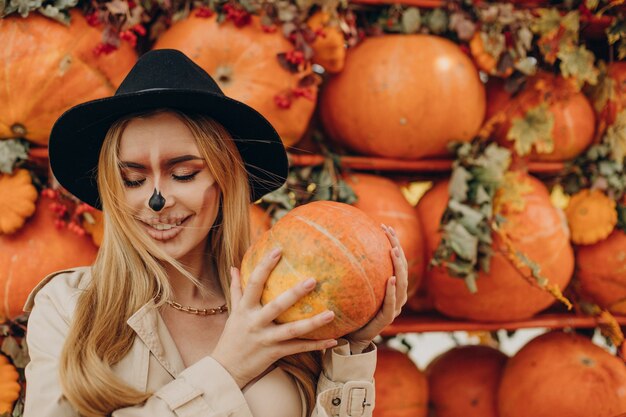 Woman with halloween make up standing by halloween pumpkins