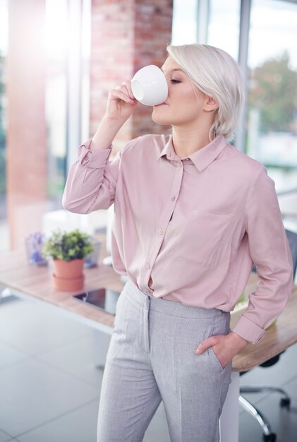 Woman with hand in pockets having a coffee