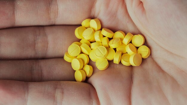 一握りの黄色い錠剤を持つ女性