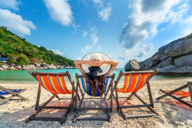 美しい熱帯のビーチの椅子のビーチに座っている帽子を持つ女性。ナンユアン島の熱帯のビーチでリラックスした女性