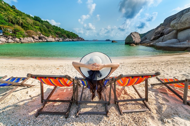 美しい熱帯のビーチの椅子のビーチに座っている帽子を持つ女性。ナンユアン島の熱帯のビーチでリラックスした女性
