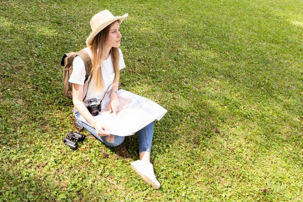 草の上に座って、よそ見の帽子を持つ女性
