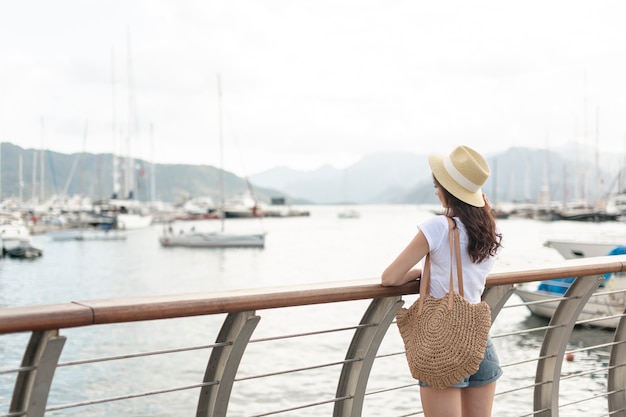 Foto gratuita donna con un cappello in piedi sul porto