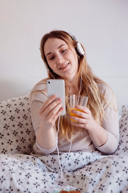 Free photo woman with headphone and juice using smartphone