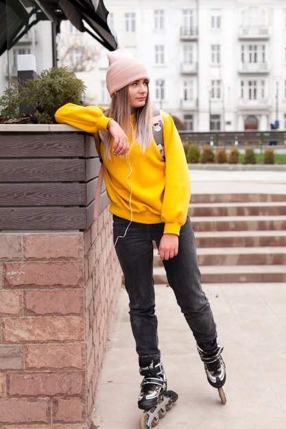 Woman with headphones and beanie posing in roller blades