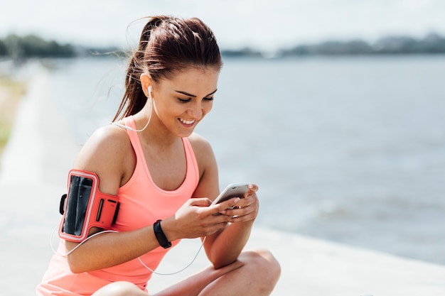 彼女の電話をチェックするヘッドフォンを持つ女性