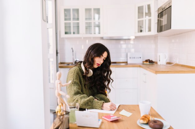 Woman with headphones drawing in kitchen