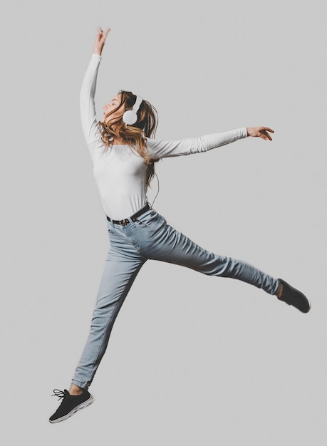 Woman with headphones jumping in the air