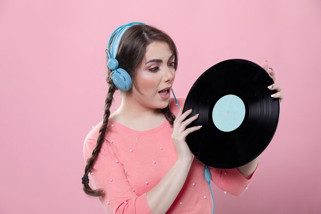 Woman with headphones looking at vinyl record