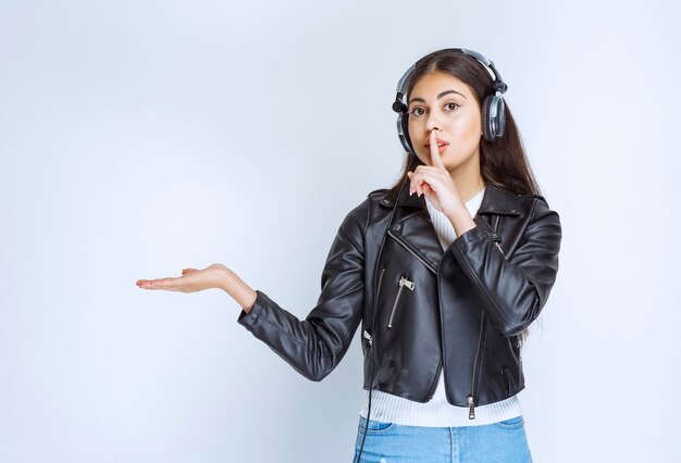 woman with headphones pointing at something aside.