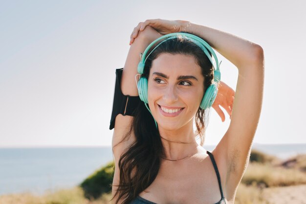 Woman with headphones stretching arms