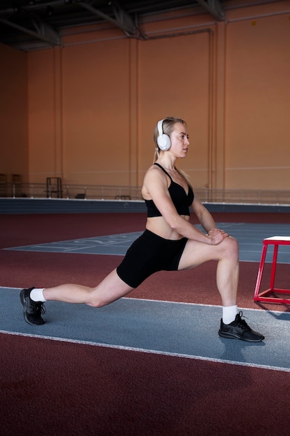 Free photo woman with headphones stretching full shot