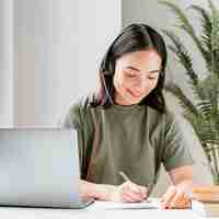 Free photo woman with headset having video call on laptop