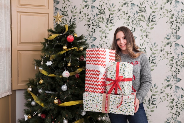 Foto gratuita donna con un mucchio di regali vicino all'albero di natale