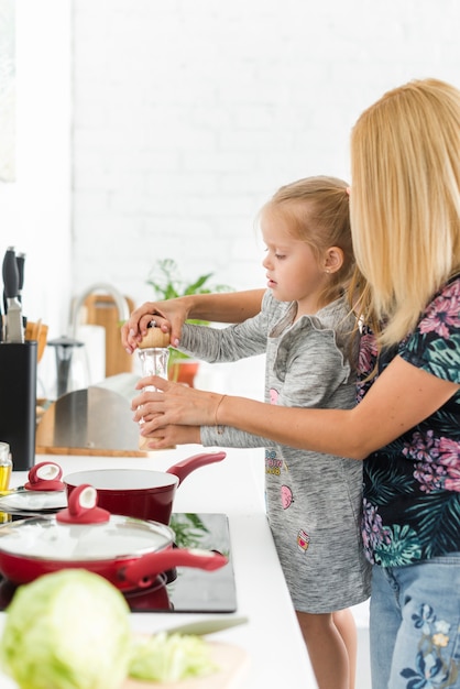 Free photo woman with her daughter holding pepper grinder