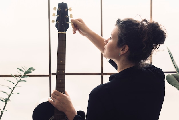 Foto gratuita donna con la sua chitarra davanti alla finestra