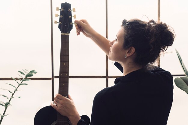 Woman with her guitar in front of window