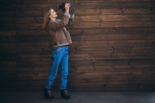 Foto gratuita donna con il suo bulldog francese dell'animale domestico su fondo di legno