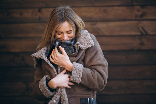 Woman with her pet french bulldog on wooden background