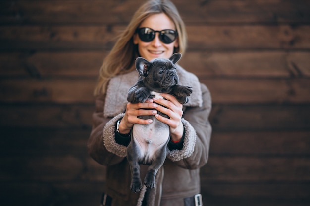 Foto gratuita donna con il suo bulldog francese dell'animale domestico su fondo di legno