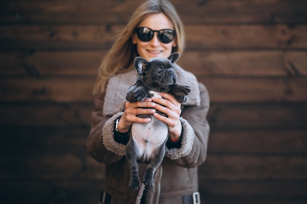 Woman with her pet french bulldog on wooden background