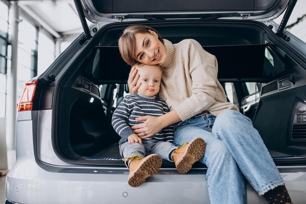 자동차 쇼룸에서 차 트렁크에 앉아 있는 그녀의 아들과 함께 여자