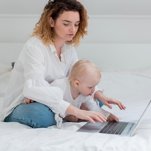 Woman with kid working in bed