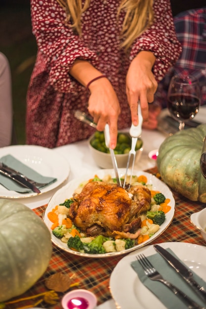 Woman with knife cutting roasted chicken