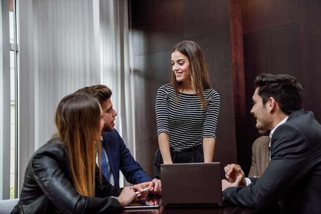 Woman with a laptop and coworkers around