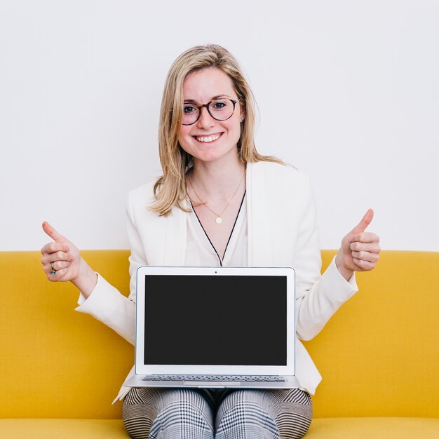 Woman with laptop gesturing thumb-up