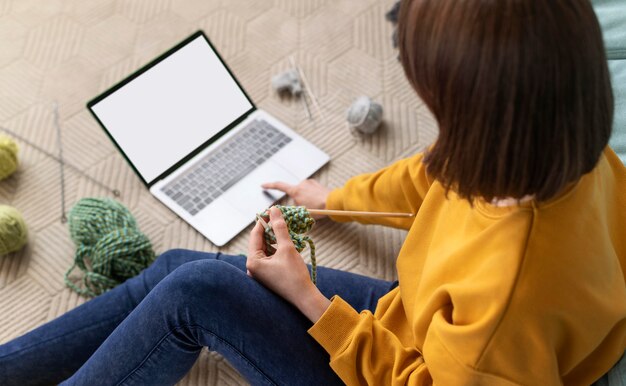 Woman with laptop knitting close up