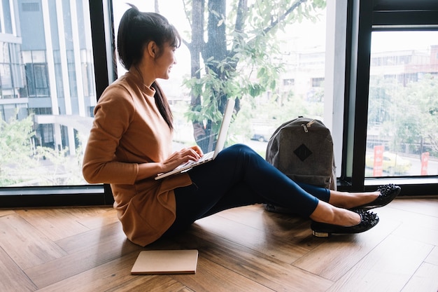 Woman with laptop looking out window