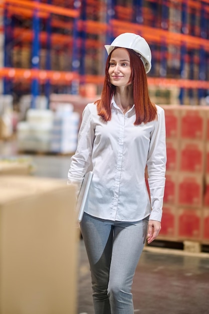 Free photo woman with laptop looking to side in warehouse