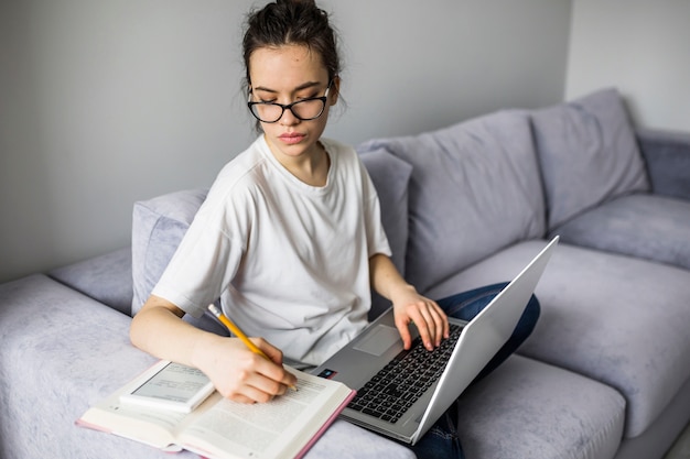 Donna con il computer portatile che fa le note in libro