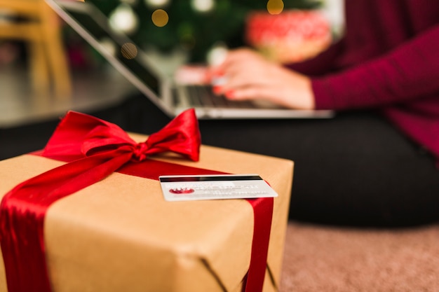 Woman with laptop near credit card and gift box