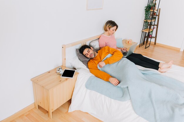 Woman with laptop near sleeping man