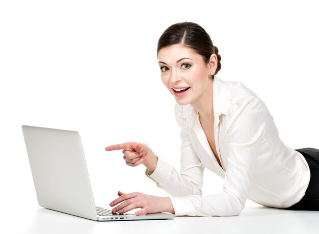 ノートパソコンを持っている女性は、床に横たわっている白いシャツの画面を指しています-白で隔離。