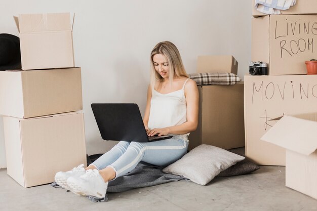 Женщина с ноутбуком в окружении картонных коробок