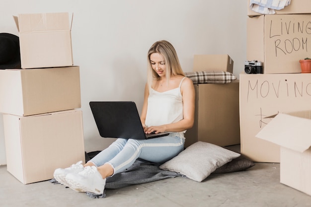 Woman with laptop surrounded by carton boxes