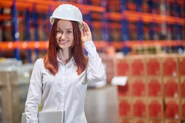 Woman with laptop touching with hand to helmet on head