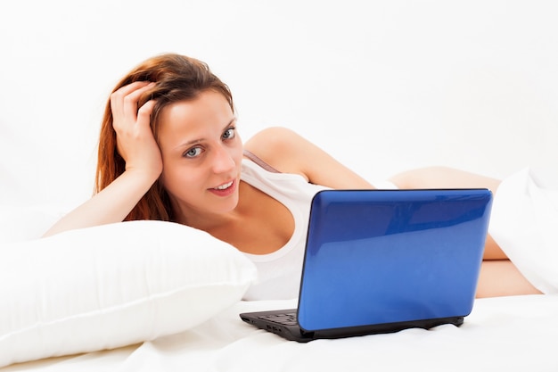 woman with laptop on white sheet