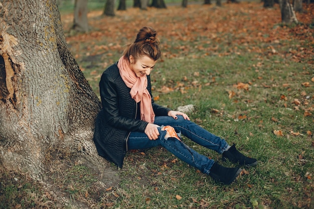 Foto gratuita donna con un infortunio alla gamba. la ragazza ferita seduta vicino all'albero. la ferita sanguina.