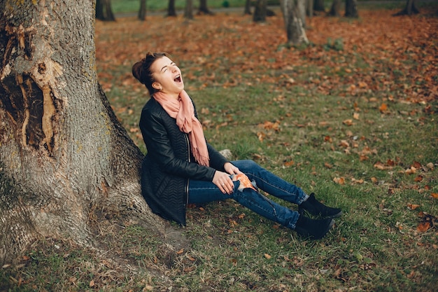 Woman with a leg injury. The wounded girl sitting by the tree. The wound is bleeding.